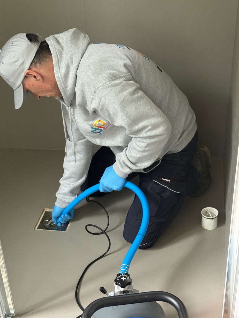 Technieker die met de elektrische veer een doucheputje ontstopt.