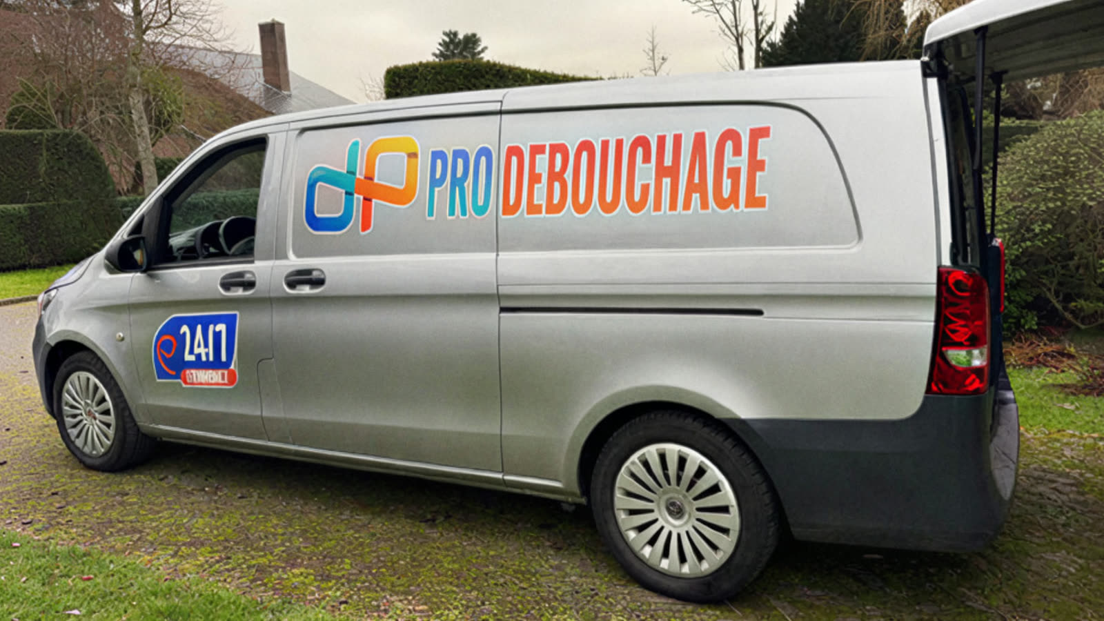 De bestelwagen in een tuin, met het Pro Débouchage logo op de zijkant.